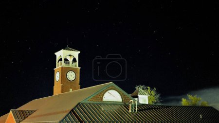 Téléchargez les photos : Un toser d'horloge sur le bâtiment de toit traditionnel la nuit avec un ciel noir - en image libre de droit