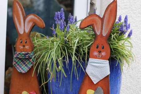 Téléchargez les photos : Un gros plan des décorations de lapins de Pâques en bois avec pot de plantes violettes derrière - en image libre de droit