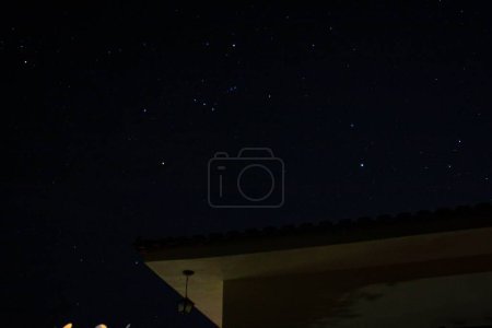 Téléchargez les photos : Un ciel étoilé pittoresque vu au-dessus du toit d'une maison - en image libre de droit