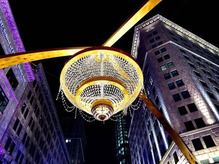 Photo for A low angle shot of a lit chandelier on a street with buildings in the background - Royalty Free Image