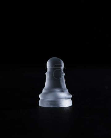 Téléchargez les photos : Plan vertical d'une pièce d'échecs sur pions en cristal isolée sur un fond noir - en image libre de droit