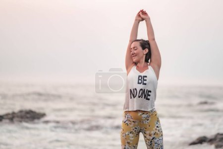 Téléchargez les photos : Une femme caucasienne s'étirant sur la plage, faisant du fitness - en image libre de droit