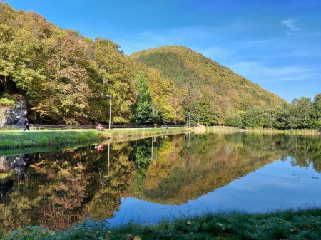 Téléchargez les photos : Les arbres d'automne reflétés dans l'étang contre un ciel bleu en Hongrie - en image libre de droit
