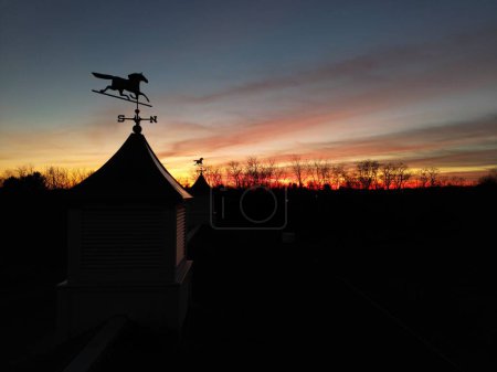 Téléchargez les photos : La silhouette des girouettes à cheval sur les coupoles et les arbres contre le ciel orange-rouge au coucher du soleil - en image libre de droit