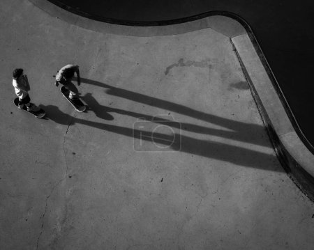 Foto de Una toma en escala de grises de TX Skaters en el parque de skate que proyecta largas sombras en la ciudad de Austin - Imagen libre de derechos