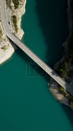 An aerial view of a bridge over a green clean lake on a sunny day