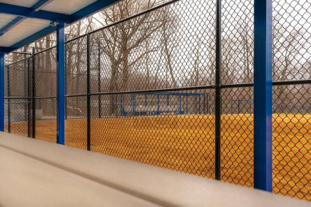 Photo for View of typical nondescript high school softball clay infield with image from inside the first base dugout. No people visible. Not a ticketed event. - Royalty Free Image