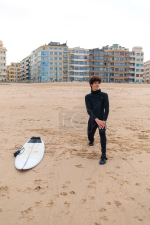 Photo for A Caucasian male surfer getting ready to go surfing in the ocean - Royalty Free Image