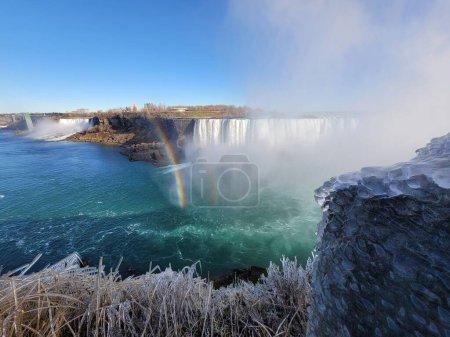 Téléchargez les photos : Une vue du paysage des chutes du Niagara partiellement recouvertes de glace avec un arc-en-ciel par une journée ensoleillée - en image libre de droit
