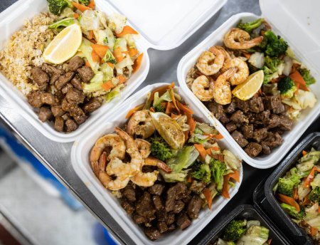 Téléchargez les photos : Une vue de dessus des boîtes à lunch avec du bœuf rôti, de la salade et des crevettes sur la table - en image libre de droit
