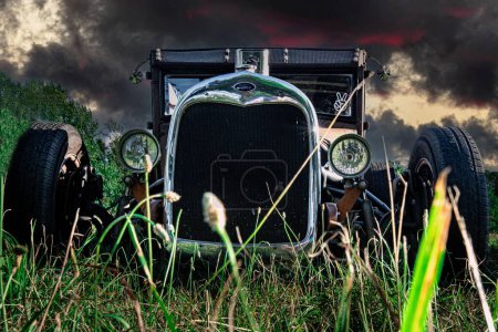 Photo for A black rat rod in a field under the stormy sky in Orillia, Ontario, Canada - Royalty Free Image