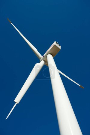 Téléchargez les photos : Plan vertical d'une éolienne sur une colline avec un fond bleu ciel - en image libre de droit
