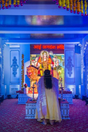 Téléchargez les photos : Une femme priant devant une idole de Maa Durga lors d'un Mandal à Mumbai pour la fête indienne de Navratri - en image libre de droit
