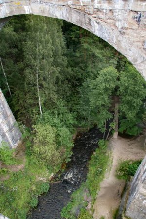 Téléchargez les photos : La petite rivière Bledzianka coulant sous le pont ferroviaire historique à Stanczyki, Mazury, Pologne - en image libre de droit