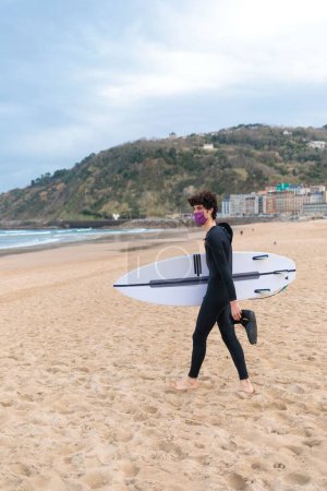 Téléchargez les photos : Un surfeur masculin caucasien se prépare à aller surfer dans l'océan - en image libre de droit