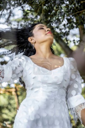 Téléchargez les photos : Attrayant Sri Lankais femelle portant une robe blanche et posant dans le parc - en image libre de droit