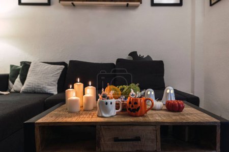 Téléchargez les photos : Les décorations d'Halloween de tasses, bougies, figures fantômes et citrouilles mis sur la table - en image libre de droit