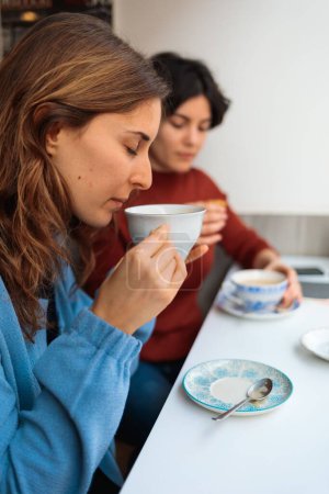 Foto de Las dos mujeres sentadas en el café, tomando café y charlando - Imagen libre de derechos