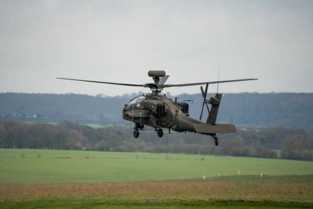 Photo for A dark grey army attack helicopter in hovers in flight during the daytime - Royalty Free Image