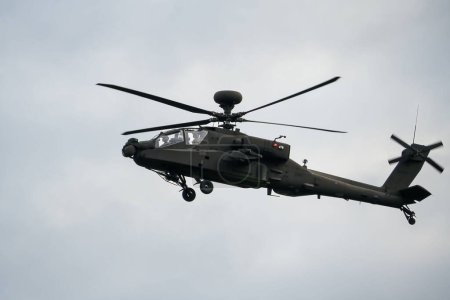 Téléchargez les photos : Un hélicoptère d'attaque gris foncé en vol contre un ciel nuageux - en image libre de droit