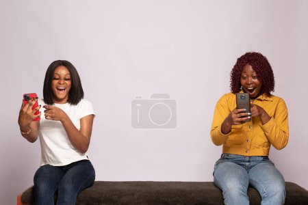 Foto de Dos jóvenes damas africanas excitadas usando sus teléfonos - Imagen libre de derechos