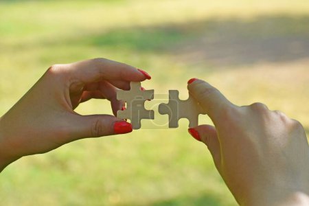 Photo for A woman's hands connecting jigsaw puzzle pieces on a natural background - concept of business strategy - Royalty Free Image