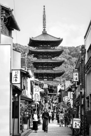 Photo for The Pagoda Hokan-ji temple viewed between buildings over a busy street, in Kyoto City center, Japan - Royalty Free Image
