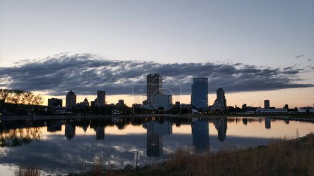 Photo for A scenic view of a skyline and its reflection visible on the surface of a lake during sunset - Royalty Free Image
