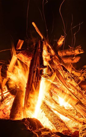 Téléchargez les photos : Un plan vertical de bois brûlant dans un feu de camp la nuit - en image libre de droit