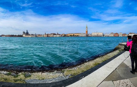 Photo for A tourist taking a picture of St. Mark's Campanile seen behind the blue sea - Royalty Free Image