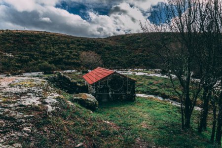 Foto de Una hermosa vista de una casa de ladrillo con un techo rojo rodeado de verdes colinas. - Imagen libre de derechos