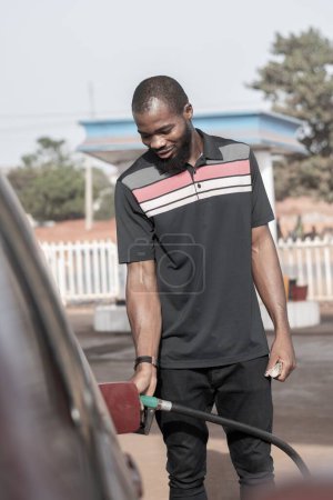Foto de Hombre africano poniendo combustible en un coche en una estación de servicio - Imagen libre de derechos