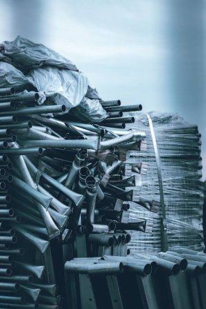 Foto de Un disparo vertical de los tubos de acero inoxidable apilados uno encima del otro con sacos en la habitación - Imagen libre de derechos