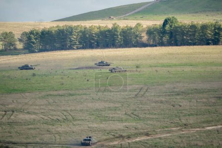 Foto de Un escuadrón de tanques de batalla del ejército que se mueven en un campo - Imagen libre de derechos