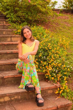 Téléchargez les photos : Plan vertical d'une belle jeune femme hispanique assise dans les escaliers d'un parc en plein jour - en image libre de droit