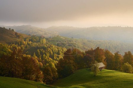 Foto de Una vista aérea de una casa en un valle verde con montañas cubiertas de bosques en el fondo - Imagen libre de derechos