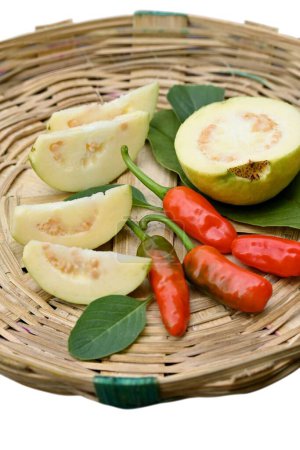 Photo for A vertical shot of sliced indian green guava and red chili peppers on a wooden basket - Royalty Free Image