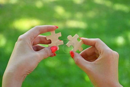 Téléchargez les photos : Les mains d'une femme reliant des pièces de puzzle sur un fond naturel concept de stratégie d'entreprise - en image libre de droit