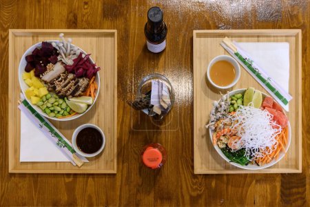 Photo for A closeup top view shot of two portions of Asian dishes with various ingredients and chopsticks - Royalty Free Image