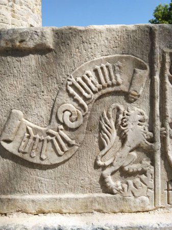 Téléchargez les photos : Une pierre sculptée symboles décorés de forme décorée sur un mur de pierre brute - en image libre de droit