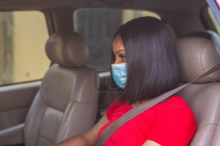 Photo for African lady with a face mask driving her car - Royalty Free Image