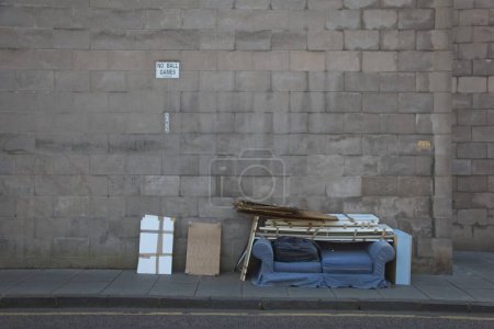 Foto de Una pared de piedra con una nota "No hay juegos de pelota" y muebles viejos en la acera de la calle - Imagen libre de derechos
