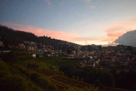 Téléchargez les photos : Coucher de soleil panoramique sur une petite ville sur une pente de montagne - en image libre de droit