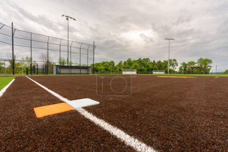 Photo for View of high school synthetic turf softball field first base with second orange safety base, looking toward home plate. - Royalty Free Image