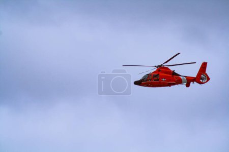Foto de Un hermoso disparo de helicóptero de la Guardia Costera roja en el cielo azul en la costa de Oregon. - Imagen libre de derechos