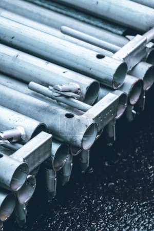 Photo for A vertical closeup shot of the snow-covered stainless steel pipes stacked on top of each in the outside - Royalty Free Image