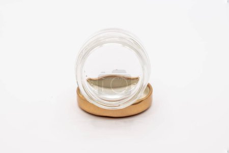 Photo for Close-up of a small empty clear jam preserve glass jar with a a bronze coloured screw down metal lid - Royalty Free Image