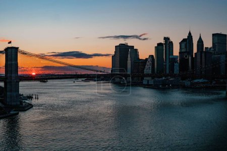 Téléchargez les photos : Le magnifique coucher de soleil sur le pont de Brooklyn près de la ville, avec un ciel orange en arrière-plan - en image libre de droit