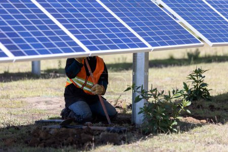 Foto de Un trabajador en un chaleco de seguridad instalando paneles solares, módulos fotovoltaicos en un campo - Imagen libre de derechos