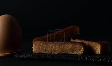Téléchargez les photos : Un gros plan de petites tranches de pain perdu et un œuf isolé sur un fond noir - en image libre de droit